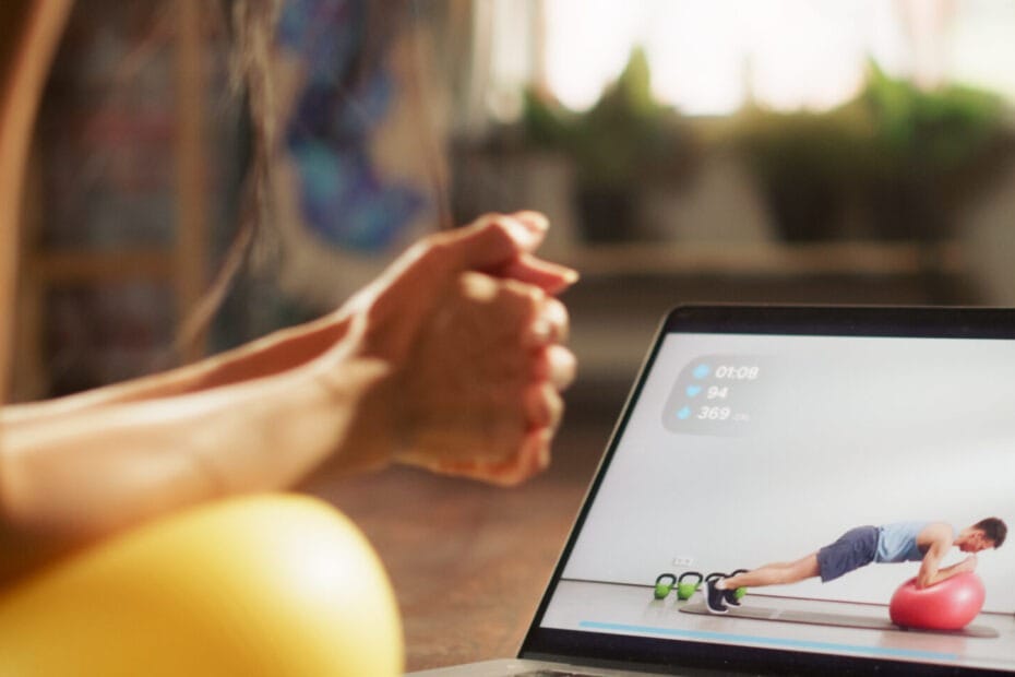 Online Coaching - Personal Trainer Köln - Personal Training Köln - Frau macht eine Plank auf einem Gymnastikball im Personal Training Online vor ihrem Laptop, auf dem sie ihren Online Coach beobachtet.