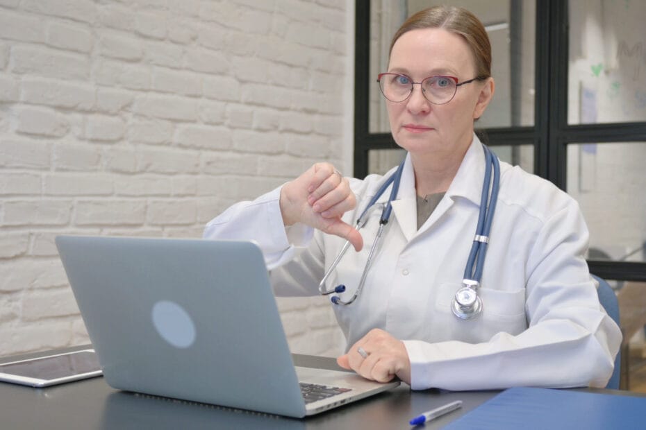 Diagnose vom Arzt bei Rückenschmerzen - Thumbs Down by Old Lady Doctor Using Laptop