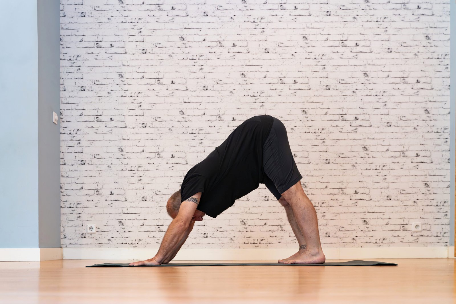 Aelterer Mann fuehrt eine Yoga-Pose schmerzfrei auf einer Matte aus
